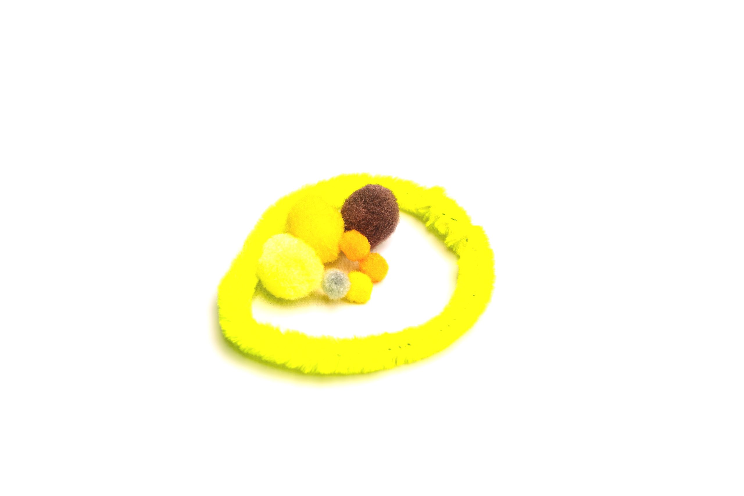 A digital photograph of a fluro yellow loop with differently sized and coloured pompoms inside. The CSR loop around the outside is like an enabler, it enables the social change to happen. The dark pompom is the visibility requirement. The yellow pompoms are the focus of the social change goals. The colourful ones are interventions that happen. The visibility is a darkish thing, it is constant. But if we deal with it, we get all these other good things. The size of the yellow social change is double the darker one, and it is not distorted by the dark one. The dark one is soft, not hard, so we can deal with it.